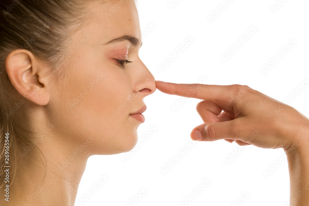profile of young woman touches her nose on white background profile of young woman touches her nose on white background