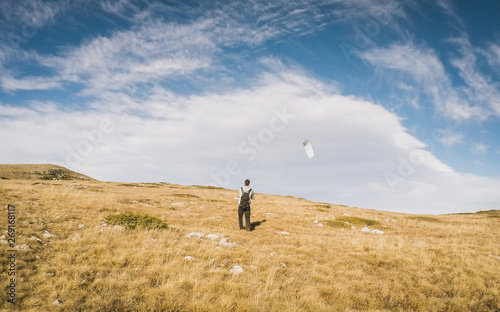 Beautiful summer sunny mountain landscape with a clear blue sky with clouds background. Crimean mountains. young man is running small paraglider. Learning paragliding. Launch a paraglider