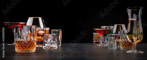 Strong alcoholic beverages  glasses and glasses  in the presence of whiskey  vodka  rum  tequila  brandy  cognac. on dark old background with selective focus
