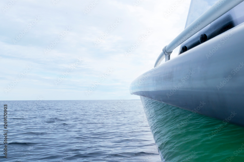 Naklejka premium Side view Speeding fishing motor boat with drops of water. Blue ocean sea water wave reflections with fast fishing yacht. Motor boat in the blue ocean. Ocean yacht. Sunset at the sailboat deck