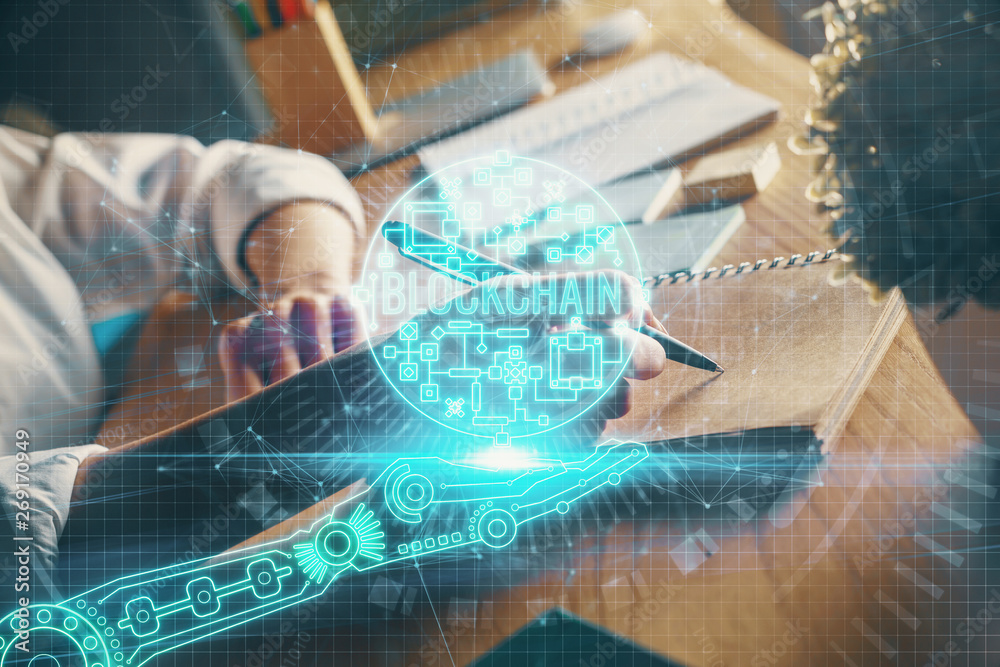 Cryptocurrency hologram, bitcoin, ico theme over hands taking notes background. Concept of blockchain. Multi exposure Cryptocurrency hologram, bitcoin, ico theme over hands taking notes background. Concept of blockchain. Multi exposure