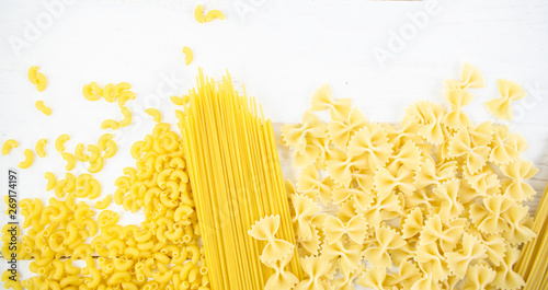 various types of pasta on a white wooden table. Italian cuisine concept, food ingredients. Flat lay. Top view, copy space