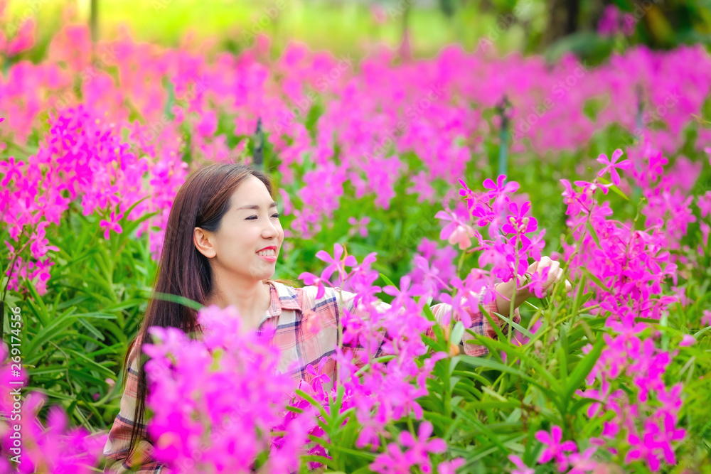 Women Asian cutting pink orchids in the garden for sale With a happy smile Women Asian cutting pink orchids in the garden for sale With a happy smile