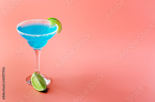 Blue margarita exotic alcoholic cocktail with tequila, liqueur, lime juice, salt and ice, summer blue background, place for text photo