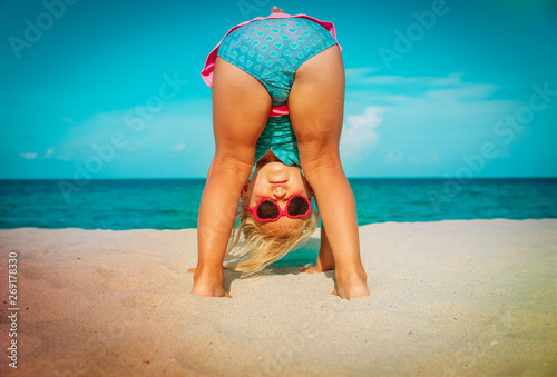 cute little girl play on beach, kid upside down on sand