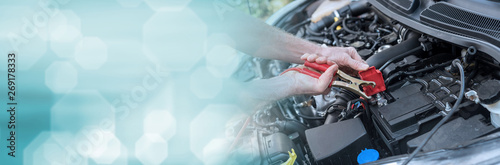 Hands of car mechanic using car battery jumper cable. panoramic banner © thodonal