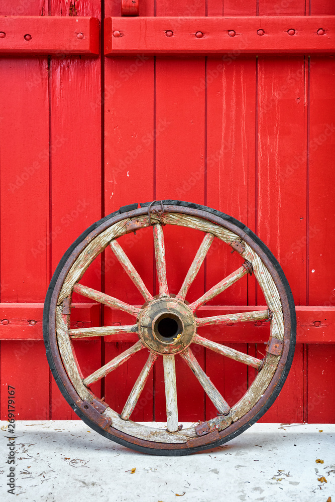Antique vintage wooden wheel against a red door