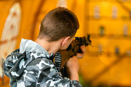 Attraction. Shooting the bottles. Caucasian boy with a rifle shooting the bottles.