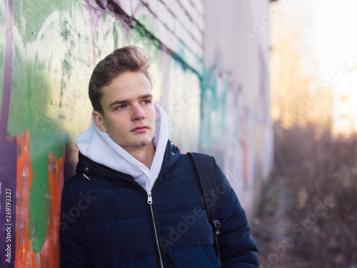 outdoor portrait of a pretty teenager against the background of a wall with graffiti © polya_olya
