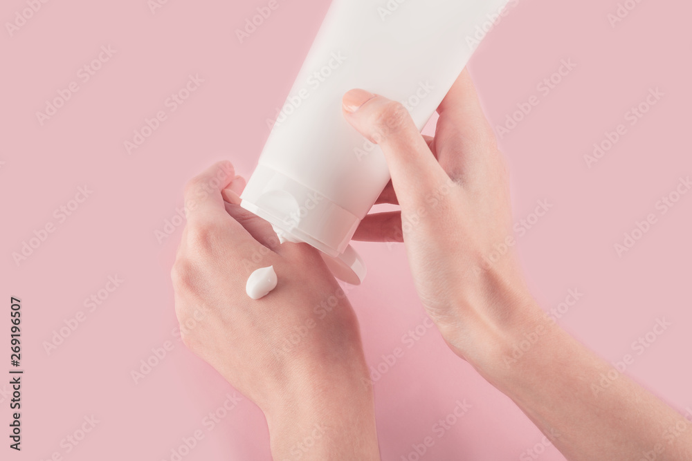 Spa treatment. Close Up of female hands applying hand cream. Woman holding cream tube and applying moisturizer cream on her beautiful hands for clean and soft skin. Spa treatment. Close Up of female hands applying hand cream. Woman holding cream tube and applying moisturizer cream on her beautiful hands for clean and soft skin.