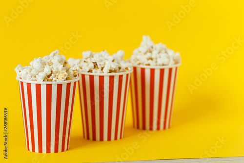 three carton bucket with cinema snack. popcorn and red cups on color yellow background. space for text