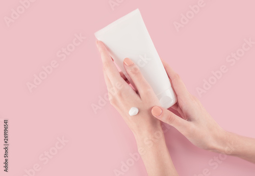Spa treatment. Close Up of female hands applying hand cream. Woman holding cream tube and applying moisturizer cream on her beautiful hands for clean and soft skin.