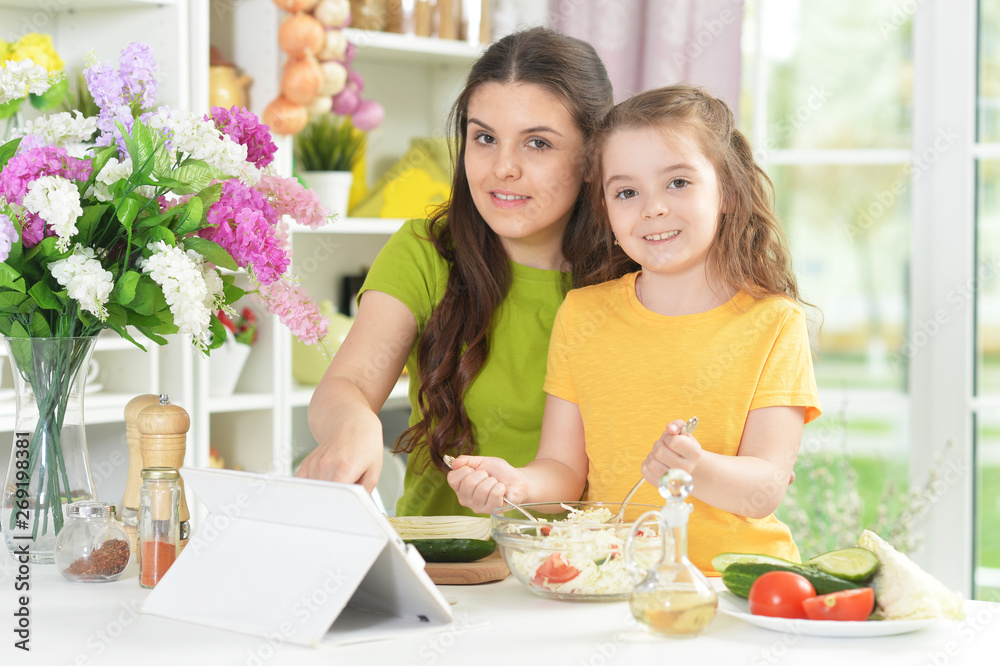 Cute little girl with her mother cooking together Cute little girl with her mother cooking together