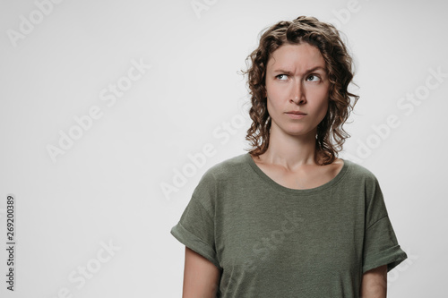 Billede på lærred Young curly woman with puzzled raises eyebrows negative facial expression