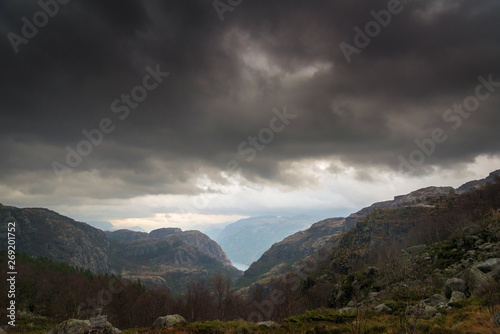 Dark stormy clouds above valley, forest and rocky mountains on background. Norway
