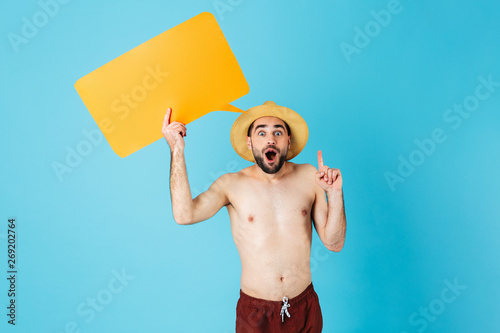 Photo of caucasian shirtless tourist man wearing straw hat smiling while holding yellow copyspace placard