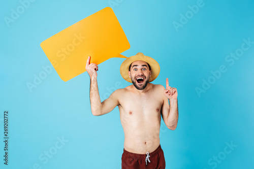 Photo of attractive shirtless tourist man wearing straw hat smiling while holding yellow copyspace placard
