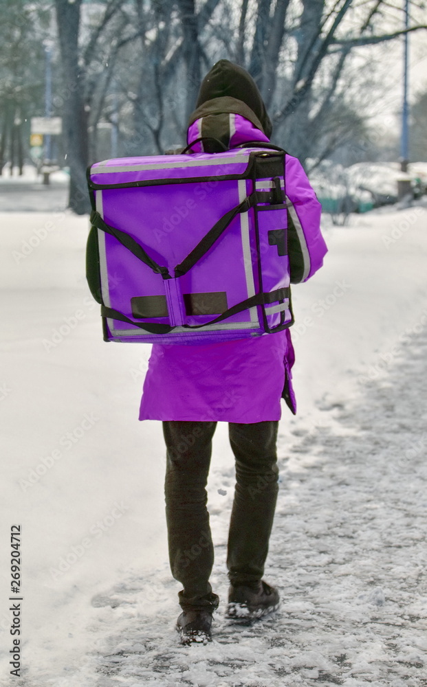 The delivery man is walking down the street. He is wearing purple overalls and a special rectangular transport backpack. Mock up blank for text and advertising