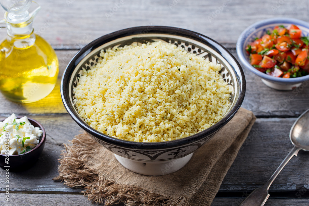 Couscous in bowl with olive oil. Wooden background. Close up. Couscous in bowl with olive oil. Wooden background. Close up.