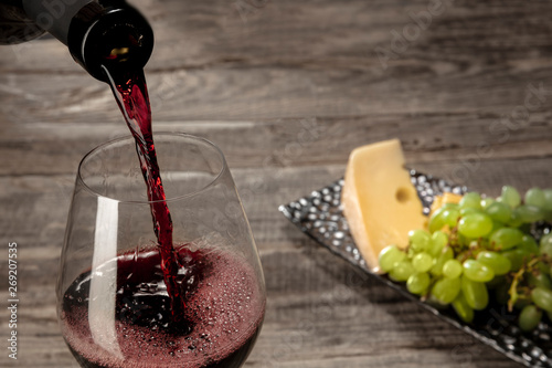 Delicisious and tasty food and drink. A bottle and a glass of red wine with fruits over weathered wooden background. Top view with copy space to insert your text or image for ad. Grape and cheeseplate photo