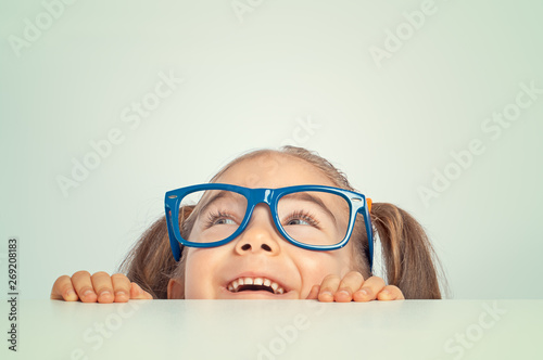 cheerful beautiful cute little girl hiding under table smiling and looking up
