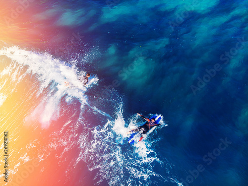 Surfer rows up to catch crest of wave in blue ocean sunlight. Concept surfing. Top view