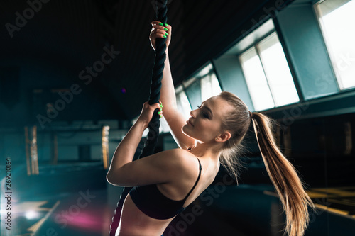 Full length narrow angle shot of a woman with climbing rope. Copyspace background with athletics healthy composition. Crossfit and fitness