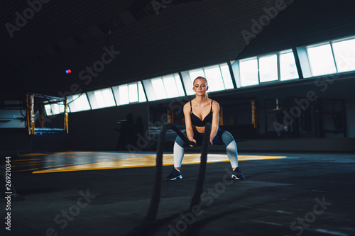 Full length wide angle shot of a young woman working out with battle ropes. Copyspace background with athletics healthy composition. Crossfit and fitness