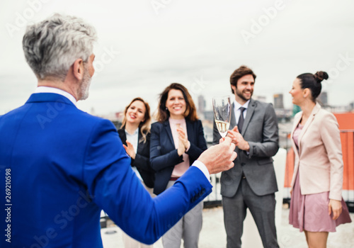 A group of joyful businesspeople having a party outdoors on roof terrace in city.