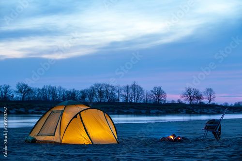 Tourist camping at sunrise on a sand river bank