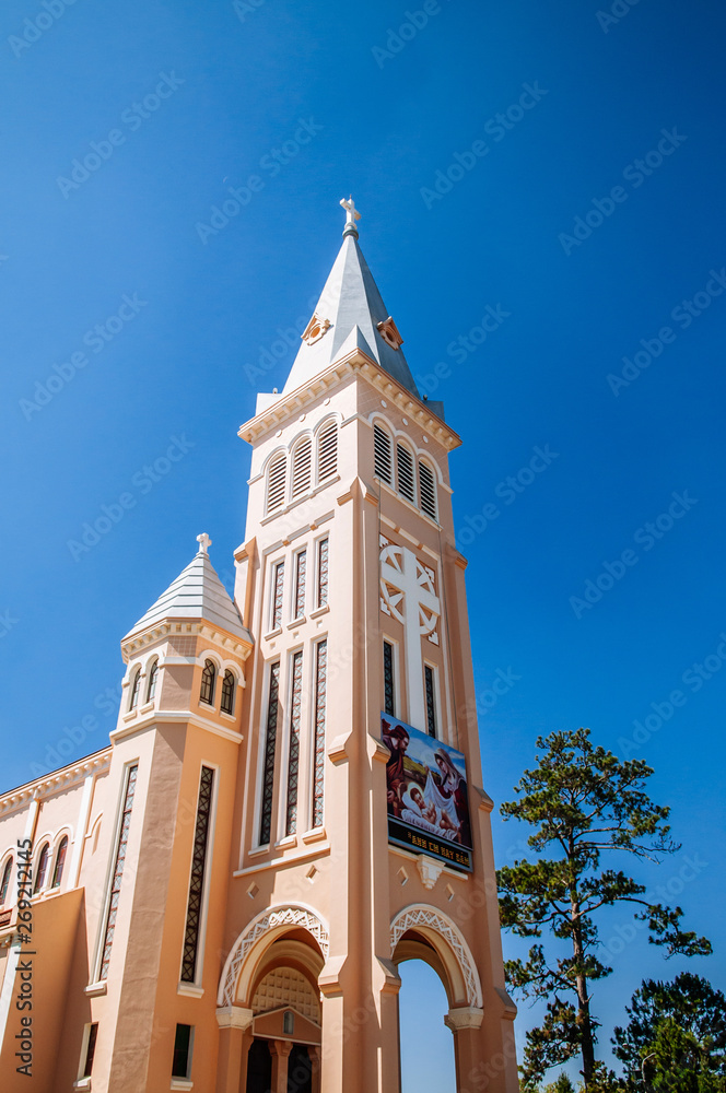 FEB 26, 2014 Dalat, Vietnam - Da Lat Cathedral yellow bell tower against bright blue clear sky in spring season