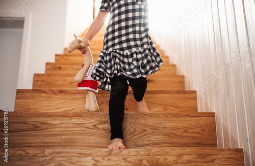 A midsection of small child with a soft toy walking down the stairs. photo