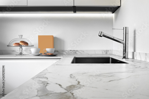 close up of a worktop of a modern kitchen in the foreground the steel sink and tap