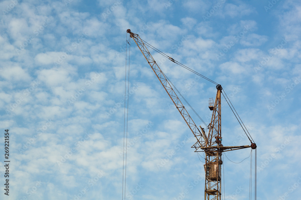 Industrial construction building crane against blue cloudy sky