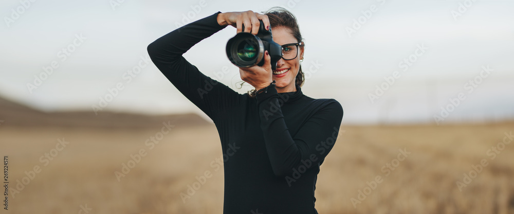 Professional female photographer shooting outdoors - obrazy, fototapety, plakaty 