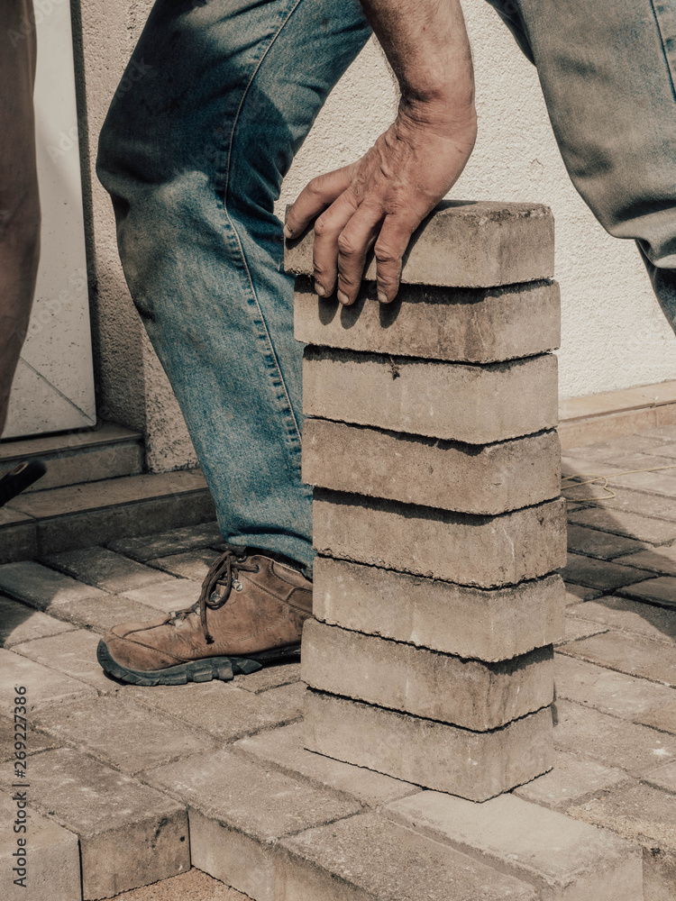 Laying gray concrete paving slabs in house courtyard driveway patio. Professional worker bricklayer, sidewalk or patio on leveled sand foundation base. Laying gray concrete paving slabs in house courtyard driveway patio. Professional worker bricklayer, sidewalk or patio on leveled sand foundation base.