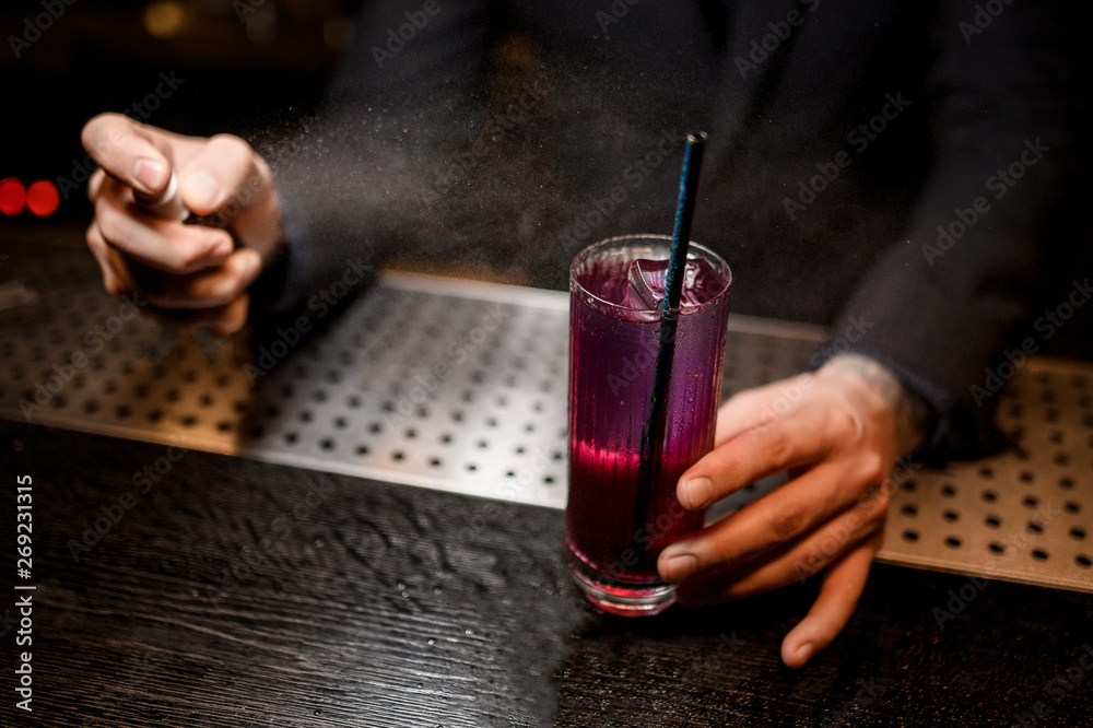 Close shot of bartender spraying to alcohol cocktail