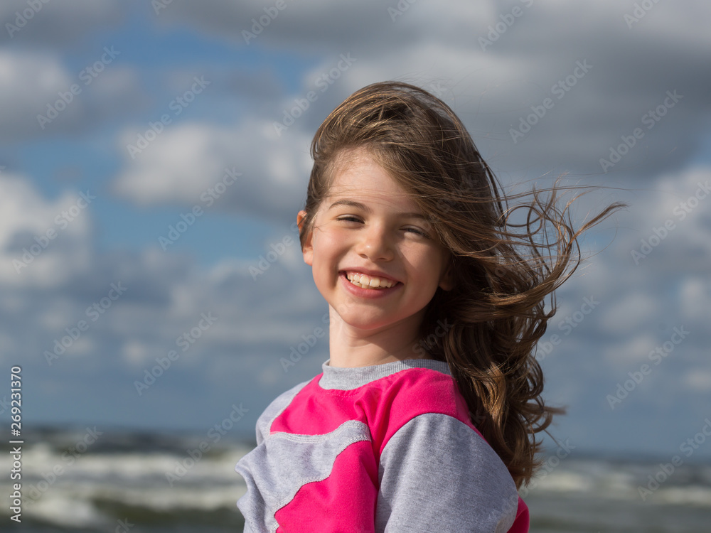 portrait of a smiling girl with wind-tousled hair on the shore of the Baltic Sea portrait of a smiling girl with wind-tousled hair on the shore of the Baltic Sea