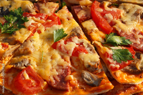 Sliced fresh hot pizza with meat, mushrooms, melted cheese and tomatoes. Closeup details and ingredients.