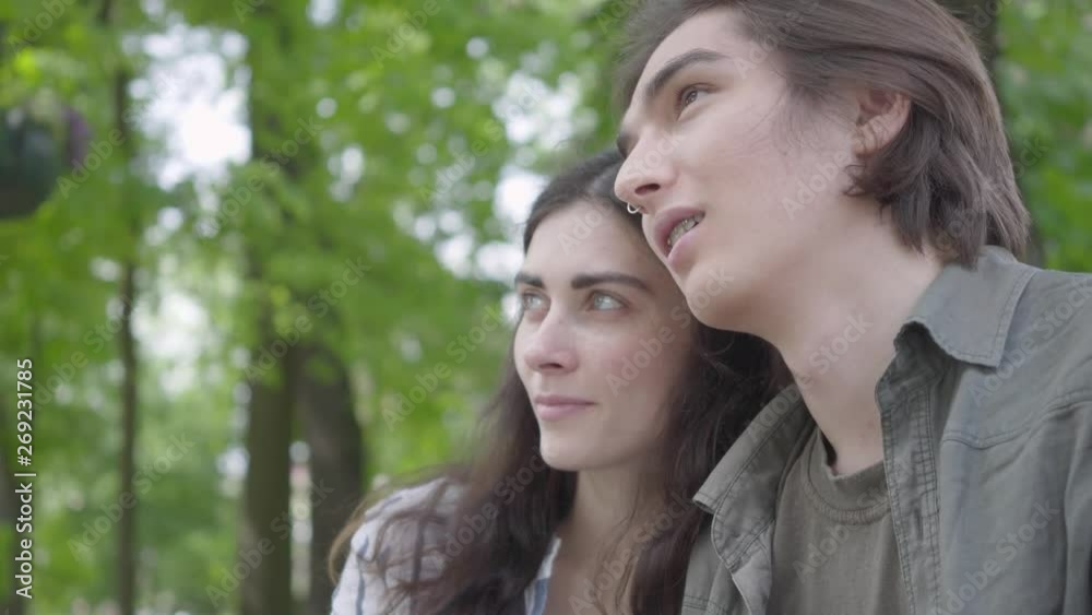 Portrait pretty young couple in love wearing casual clothes sitting at the bench talking and holding hands. Happy girl and boy spending time together in the park. Leisure outdoors Portrait pretty young couple in love wearing casual clothes sitting at the bench talking and holding hands. Happy girl and boy spending time together in the park. Leisure outdoors