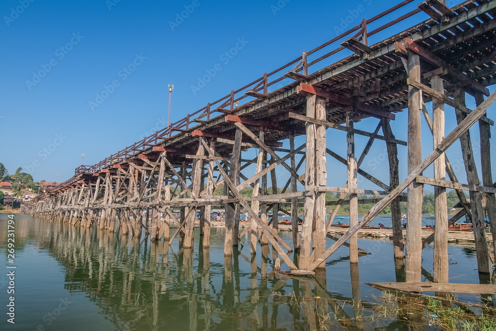 view of Mon bridge with blue sky background know as wooden bridge longest in Thailand, Sangklaburi, Kanchanaburi, Thailand. view of Mon bridge with blue sky background know as wooden bridge longest in Thailand, Sangklaburi, Kanchanaburi, Thailand.