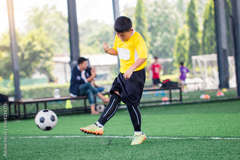 blurry ball with Asian kid soccer player speed run to shoot ball to goal on artificial turf. blurry ball with Asian kid soccer player speed run to shoot ball to goal on artificial turf.