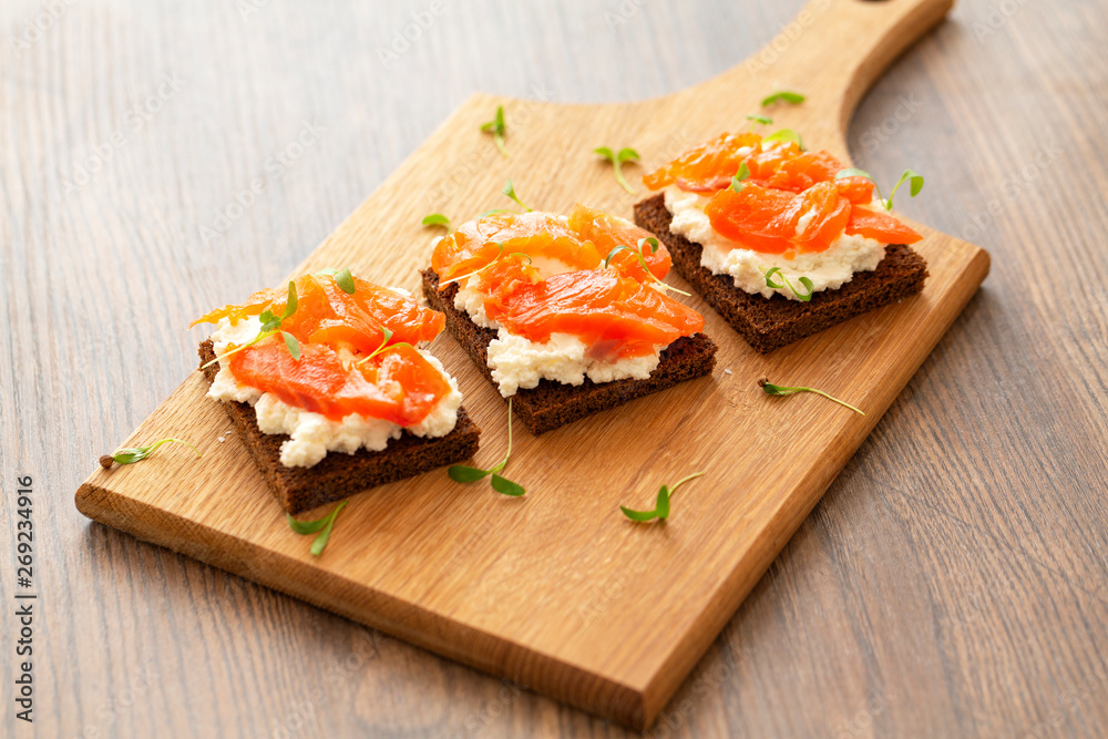 Canape with smoked salmon and cream cheese on wooden board. Selective focus Canape with smoked salmon and cream cheese on wooden board. Selective focus