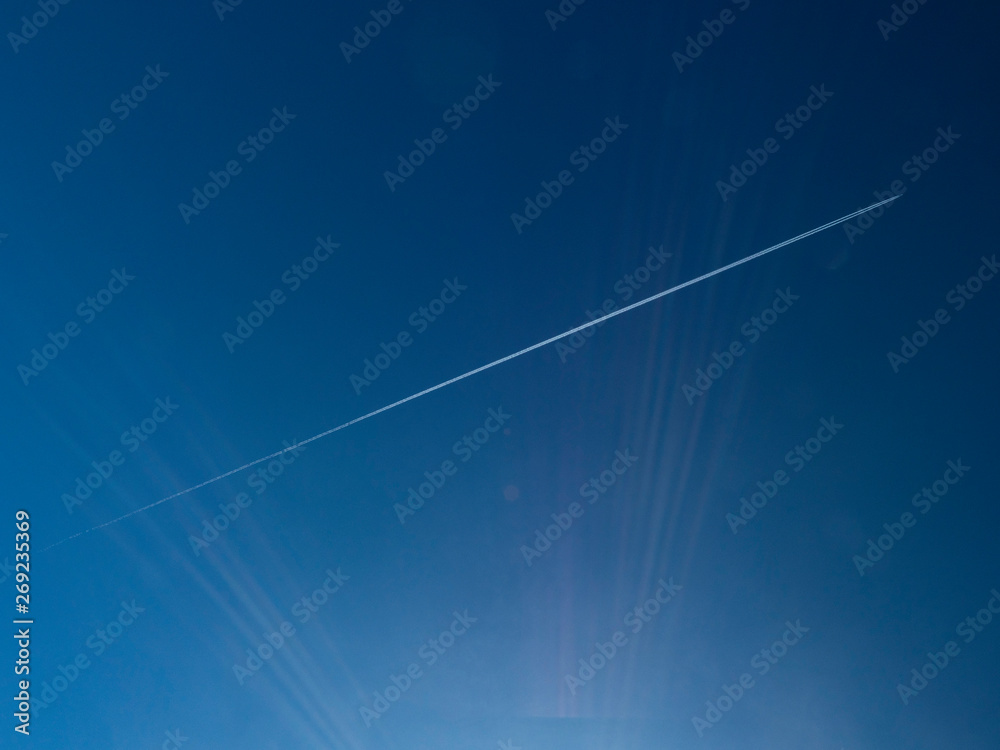 scia di un aereo nel cielo con raggi solari - obrazy, fototapety, plakaty 
