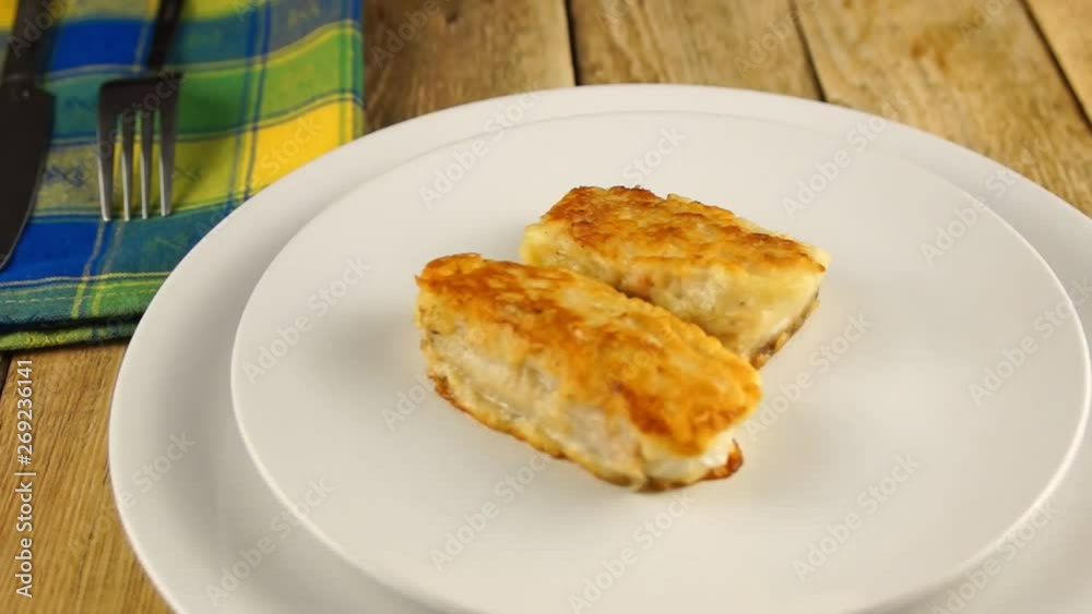 Deep-fried battered cod fillets, in a white plate on a wooden background. Close-up Deep-fried battered cod fillets, in a white plate on a wooden background. Close-up