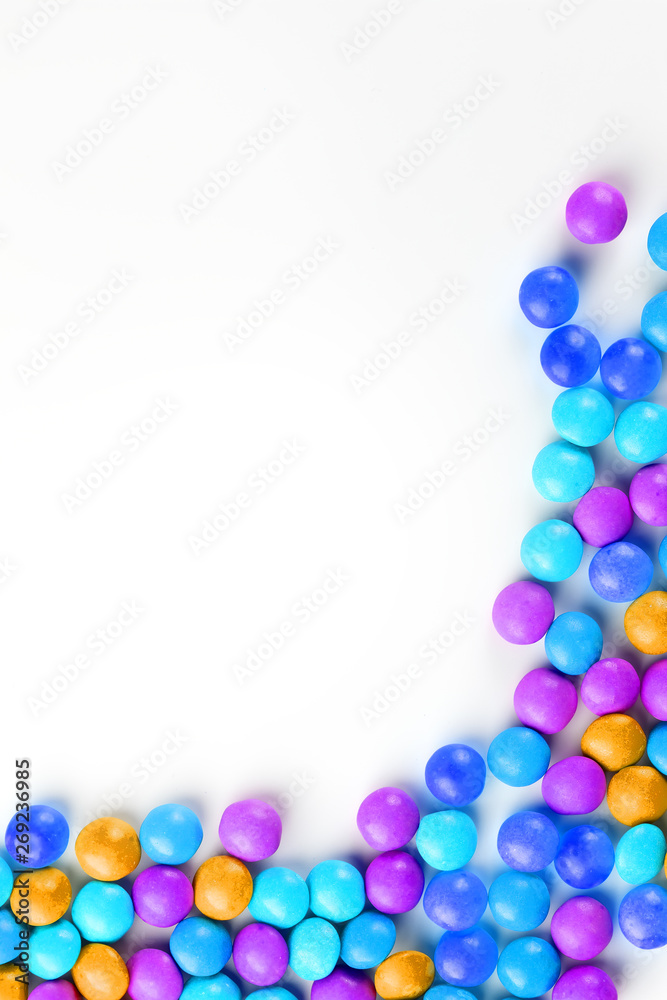Frame of multi-colored candies close up. Rainbow colored dragee multicolored glaze on a white background Frame of multi-colored candies close up. Rainbow colored dragee multicolored glaze on a white background