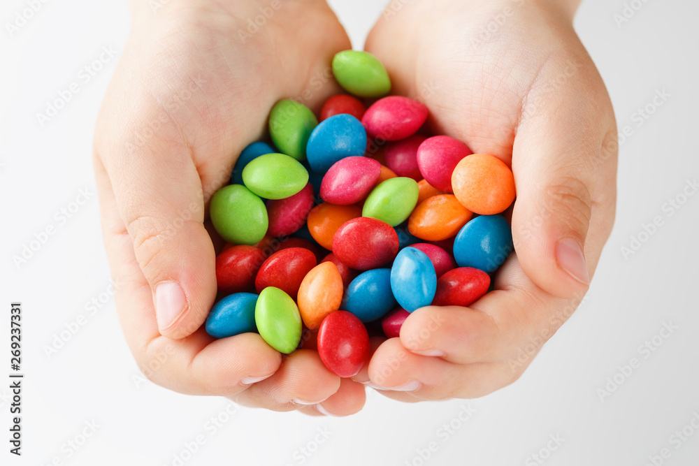 Multicolored candies in the hands of a child on a white isolated background Multicolored candies in the hands of a child on a white isolated background