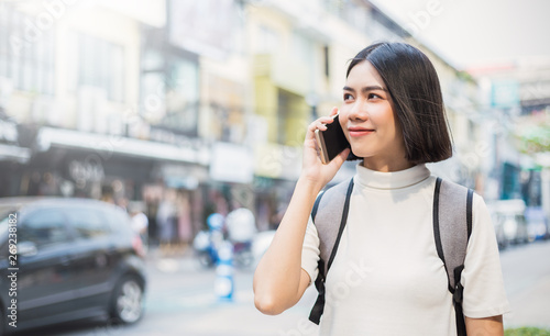 Smiling young asian woman talking on smart phone with backpack in the city. Beautiful asian girl walking to school. Education technology communication travel lifestyle people back to school concept