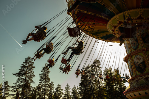 Kouvola, Finland - 18 May 2019: Ride Swing Carousel in motion in amusement park Tykkimaki and aircraft trail in sky.