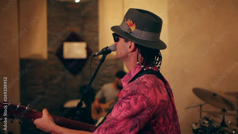 singer played the guitar in front of the microphone of a recording booth in a recording studio